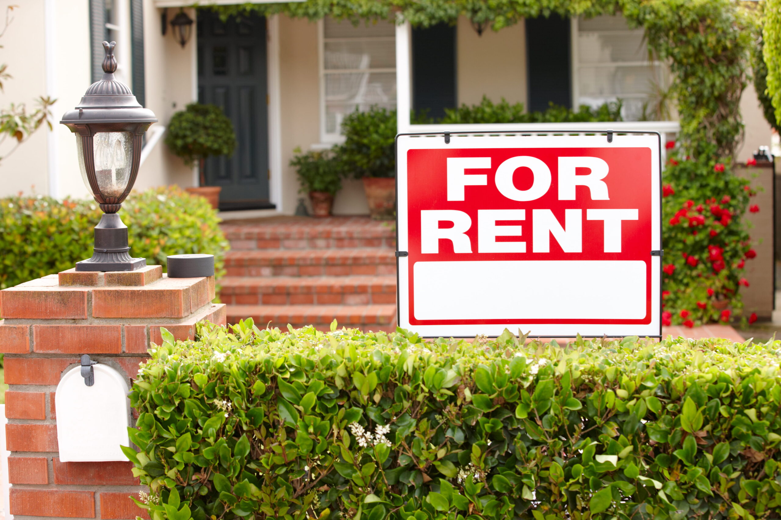 Home with a for rent sign in front.